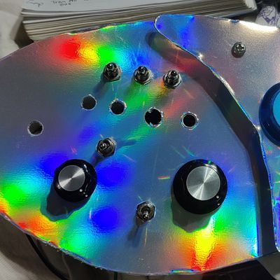 a shiny holographic rainbow pickguard with toggles, knobs, and yet-unfilled holes